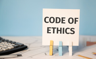 CODE OF ETHICS on a sticker beside a calculator and a pen. Finances and business concept.
