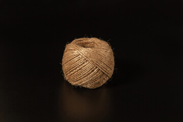 A ball of twine. A ball of packet thread. A ball of linen thread. A ball of thick brown thread. On an isolated black background. Side view. Background for text or design. Banner design.