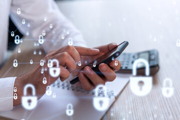 A programmer is browsing the Internet in smart phone to protect a cyber security from hacker attacks and save clients confidential data. Padlock Hologram icons over the typing hands. Formal wear.