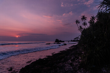 Fototapeta na wymiar Pomarańczowo fioletowe niebo z zachodzącym słońcem, tropikalny krajobraz wybrzeże z oceanem.