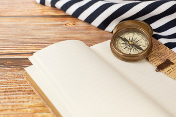 The compass, sea ​​blouse and open notebook in vintage style are on a wooden background. Free space for text.