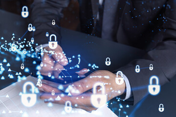 A programmer is browsing the Internet in smart phone to protect a cyber security from hacker attacks and save clients confidential data. Padlock Hologram icons over the typing hands. Formal wear.