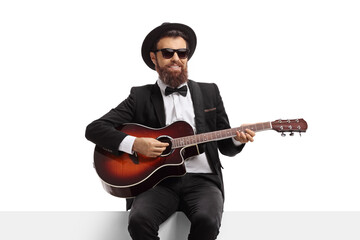 Obraz premium Bearded man with an acoustic guitar sitting on a white panel