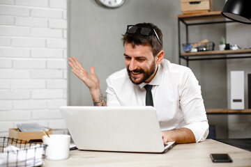 Young businessman using laptop in his office. Happy man working on computer at his workplace..