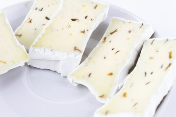 Cheese with white mold and seasoning sliced on white plate, close-up