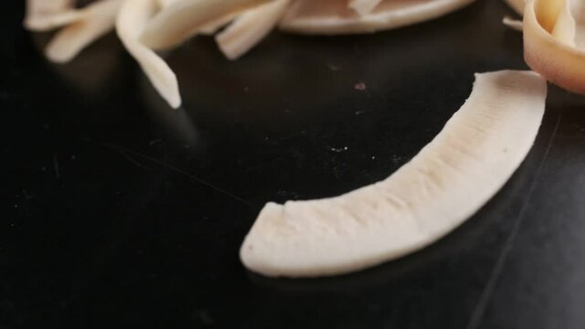 Coconut chips on a dark table close-up. Black background, slow motion.