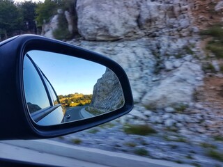 sunny day on the mountain in the rearview mirror during drive