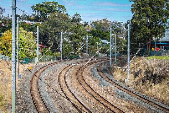 Four railroad rails curve out of site in populated area of Brisbane Australia.