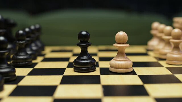 Chess players place white and black pawns on the playing field. Close-up of a chess game on a board