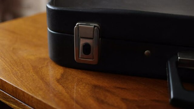 A Man Closes An Old Business Suitcase. A Black Vintage Briefcase Is Lying On A Wooden Table .