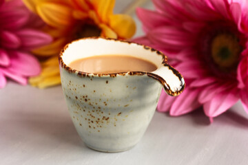 Cup of coffee, coffee with milk, gerber daisy on grey background. Coffee and flowers in spring.