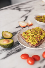 Avocado, tomatoes, lemon, onions, guacamole on bread. Ingredients on a marble table