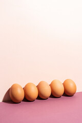 Brown eggs in cellophane on pastel pink background. modern concept of minimalism