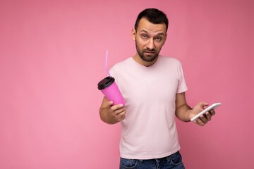 Photo of handsome young unshaven brunette man with beard wearing everyday light pink t-shirt...
