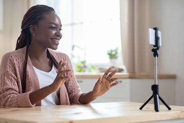 Young african american female blogger recording new video on smartphone at home