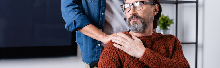 young man touching shoulder of thoughtful dad looking away at home, banner