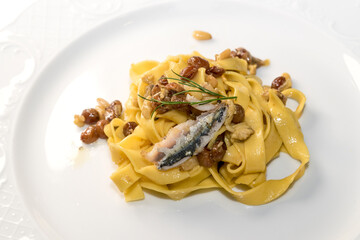 Tagliatelle with le sardine - Sicilian pasta with raisins, pine nuts and fennel, close up in white dish