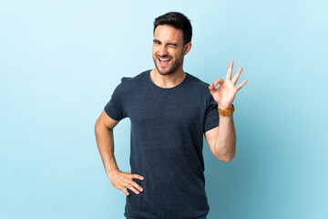 Fototapeta premium Young handsome man over isolated background showing ok sign with fingers