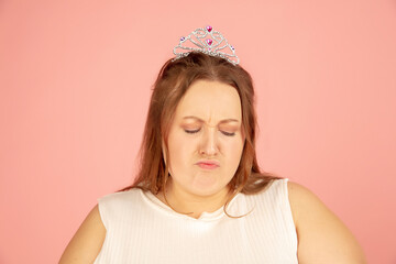 Close up. Beautiful plump caucasian plus size model in fairy's outfit on pink studio background. Concept of inclusion, human emotions, facial expression, sales, body positive. Copyspace for ad.