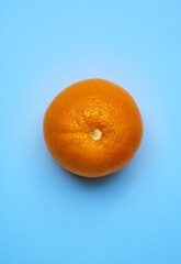 Fruit placed in the center on a plain blue background. Appetizing orange on a homogeneous light blue background. 
