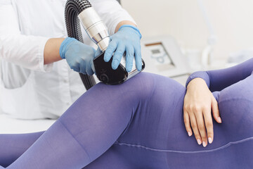 Woman in special purple suit getting anti cellulite massage in a spa salon. Lpg massage procedure. Hands of therapist holding lipomassage tool