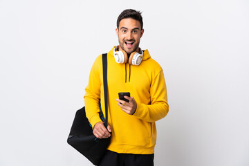 Young sport man with sport bag isolated on white background surprised and sending a message