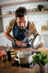  Young man cooking in the kitchen. Happy man preparing delicious food at home..