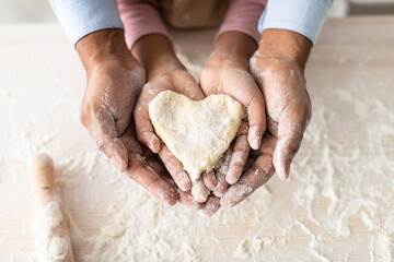 Black man and girl holding dough in heart shape