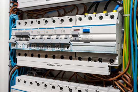 Single phase fuses in OFF and ON position and residual current protection in ON position. Many gray switches in a row, home fuse box.