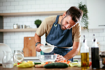 Fototapeta na wymiar Happy man baking in the kitchen. Man making fresh pasta at home.