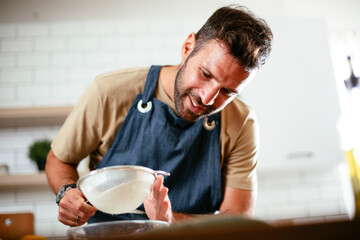Happy man baking in the kitchen. Man making fresh pasta at home.