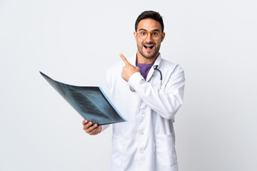 Young doctor man holding a radiography isolated on white background pointing finger to the side