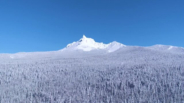 Flying towards snow-covered Mt Thielsen, over snow-covered forest on a clear, blue-bird afternoon with no clouds.