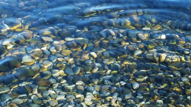 Reflets de lumi&egrave;re par des vagues sur des pierres