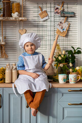a small child plays in the kitchen as a cook