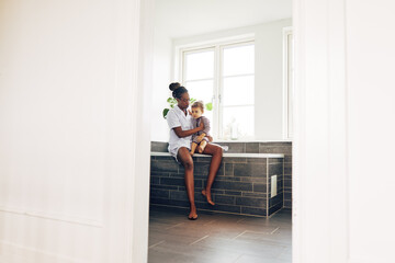 Young mom and little girl sitting in their bathroom at home