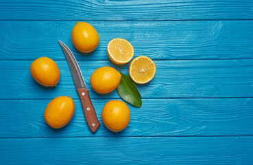 Obraz premium Fresh ripe lemons and knife on blue wooden table. Top view with copy space.