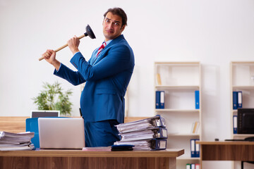 Young male employee holding plunger in funny concept