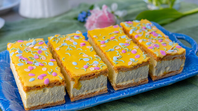 Tompouce cakes with whipped cream and yellow icing served in sunny spring garden