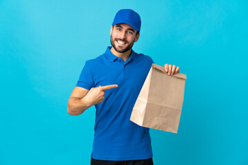Delivery man with beard isolated on blue background and pointing it