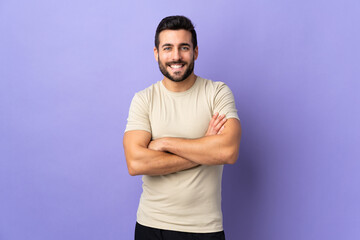 Young handsome man with beard over isolated background keeping the arms crossed in frontal position