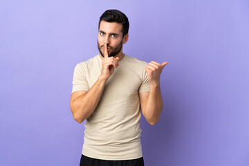 Naklejka premium Young handsome man with beard over isolated background pointing to the side and doing silence gesture