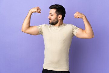 Young handsome man with beard over isolated background doing strong gesture