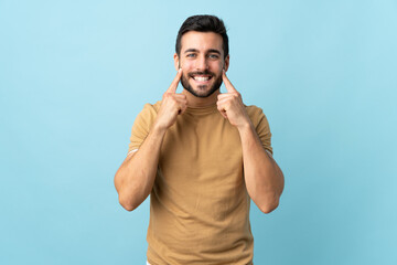 Naklejka premium Young handsome man with beard over isolated background smiling with a happy and pleasant expression