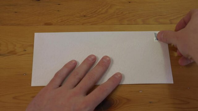 Man Places Stamp on Blank Envelope, First Person Point of View