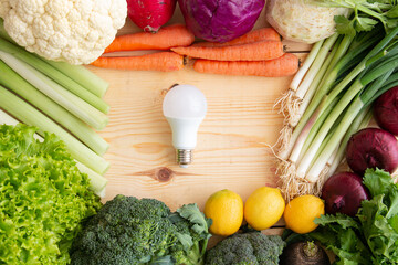 the led bulb stands on wood filled with vegetables. health and energy saving idea for a long time.