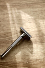 Reusable metal safety razor on wooden background. Selective focus.