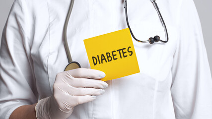 Cropped view of doctor in a white coat and sterile gloves holding a note with word - DIABETES