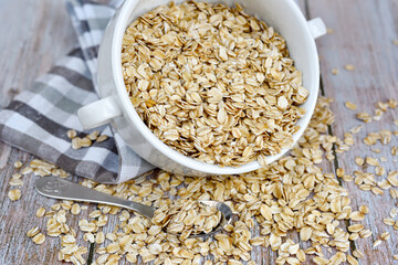 Oat flakes uncooked in a white bowl on rustic table. Healthy food for breakfast