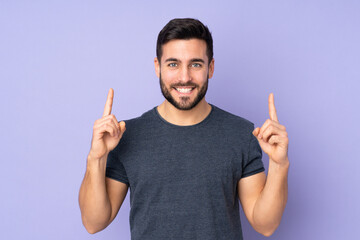 Caucasian handsome man pointing up a great idea over isolated purple background